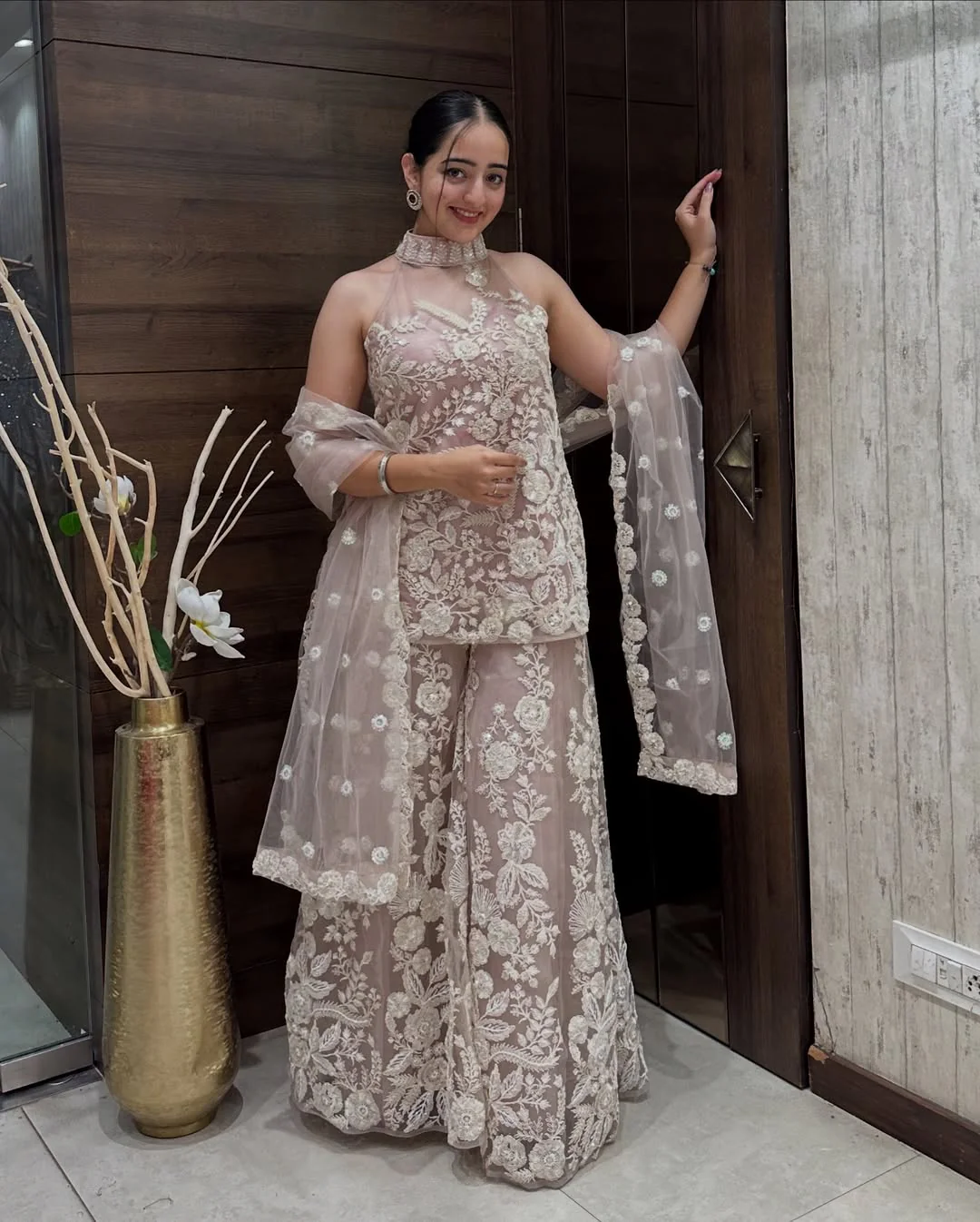 Model wearing an a-symmetrical butterfly net top with delicate embellishments, paired with matching sharara pants and dupatta